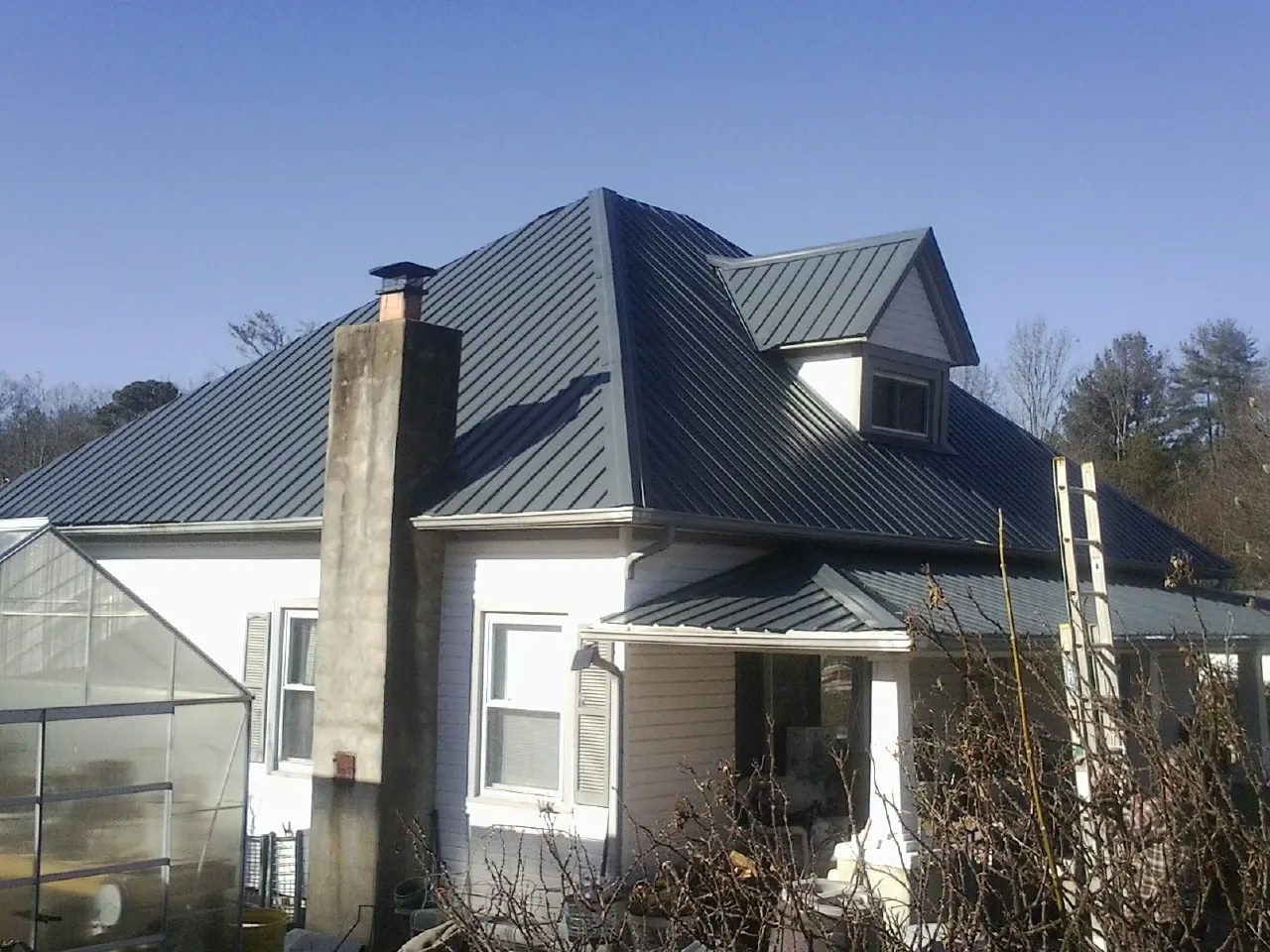 Dark blue standing seam metal roof on a white farmhouse with dormer — Slate & Tile Roof Repair by Roofing Brothers in Rolla