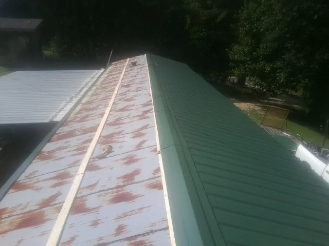 Old rusted panels beside newly installed green metal roofing — Wind Damage Roof Repair by Roofing Brothers in Rolla