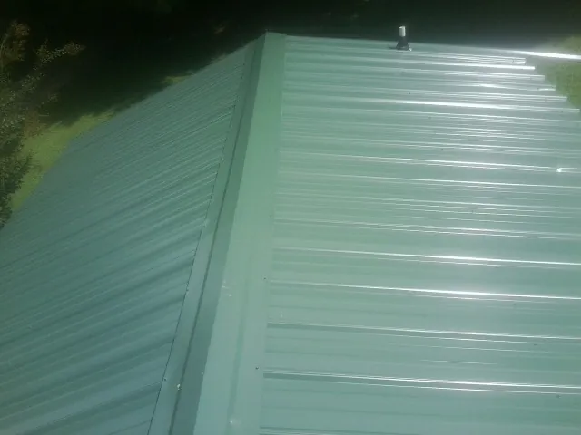 New green metal panels meeting at the ridge of a roof — Flat Roof Repair work by our crew in Rolla