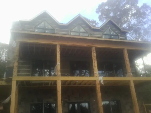 Dormers and porch framing on a large log home under construction — Roof Coating work by our crew in Rolla