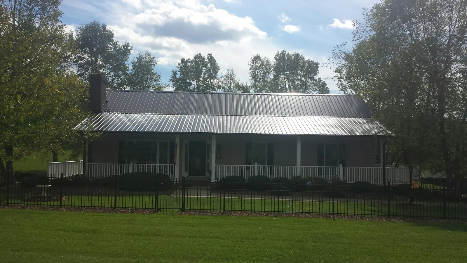 Gray metal roof on a brick ranch with a full width front porch — Gutter Guard Installation work by our crew in Rolla