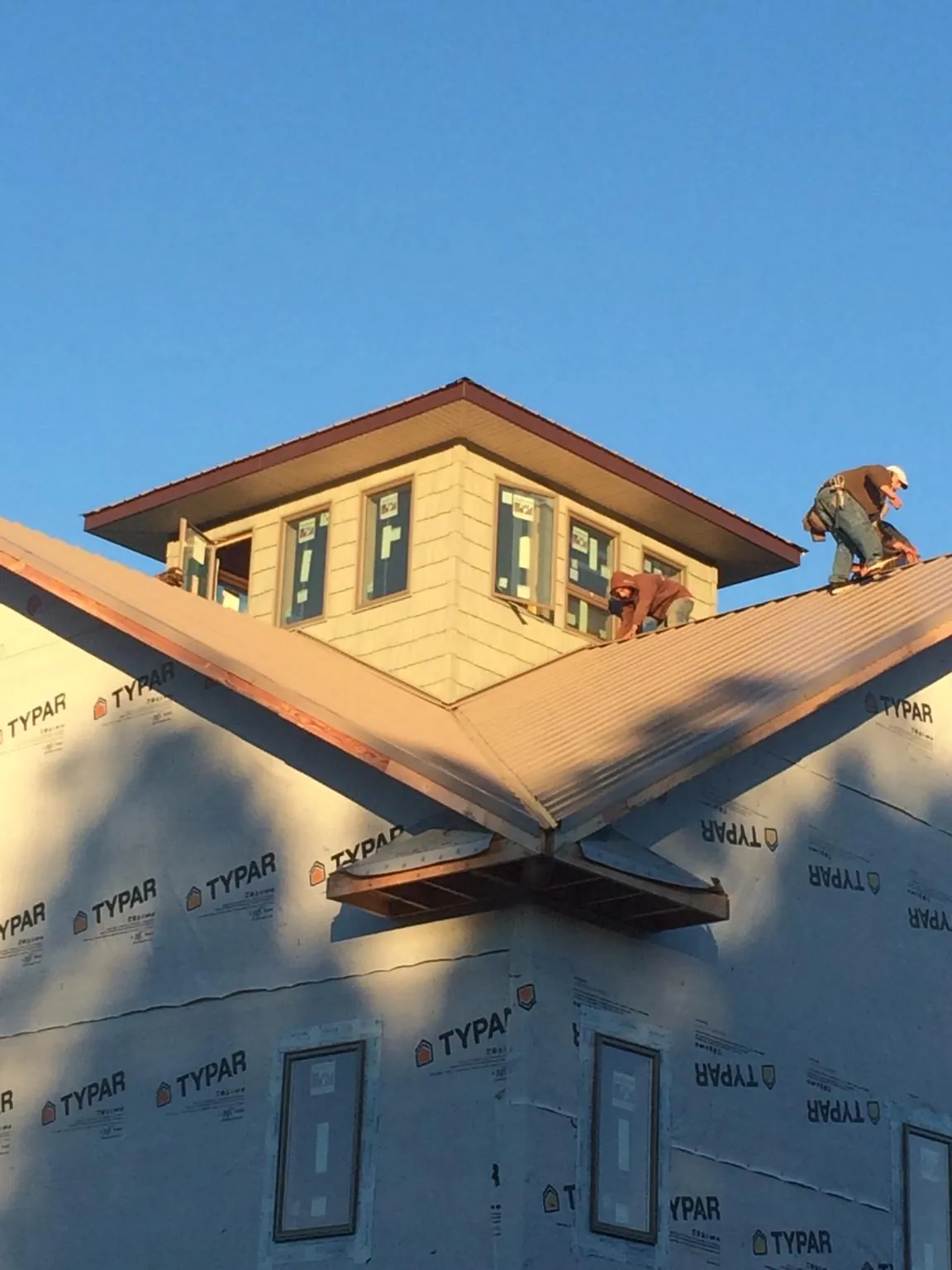 Roofers working around a rooftop cupola on a new metal roof at sunset — Roof Waterproofing in Rolla by Roofing Brothers